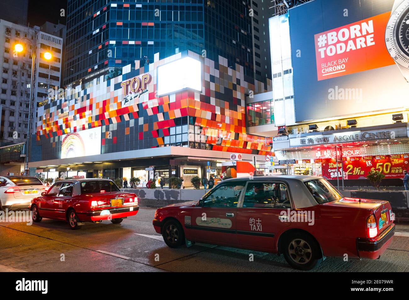 Hong Kong bei Nacht beleuchtete Schaufensterläden, Wolkenkratzer und rote Taxis viel Verkehr in der Stadt. Tsim Sha Tsui Bezirk, Kowloon, China. Stockfoto