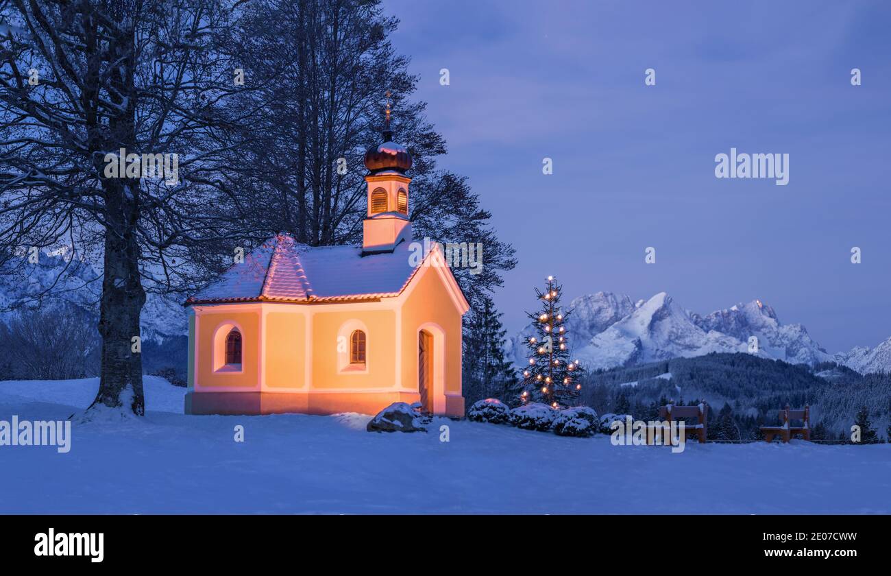 Weihnachtsbaum neben schöner Kirche in den Bergen - Nacht im Mondschein Stockfoto