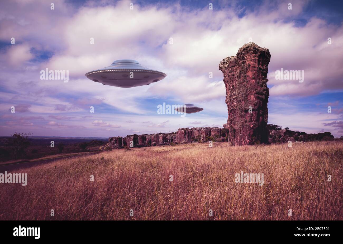 Zwei UFOs fliegen über uralte Felsen. Nicht identifizierte fliegende Objekte fliegen über den Himmel. 3D-Illustration mit Clipping-Maske im Lieferumfang enthalten. Stockfoto