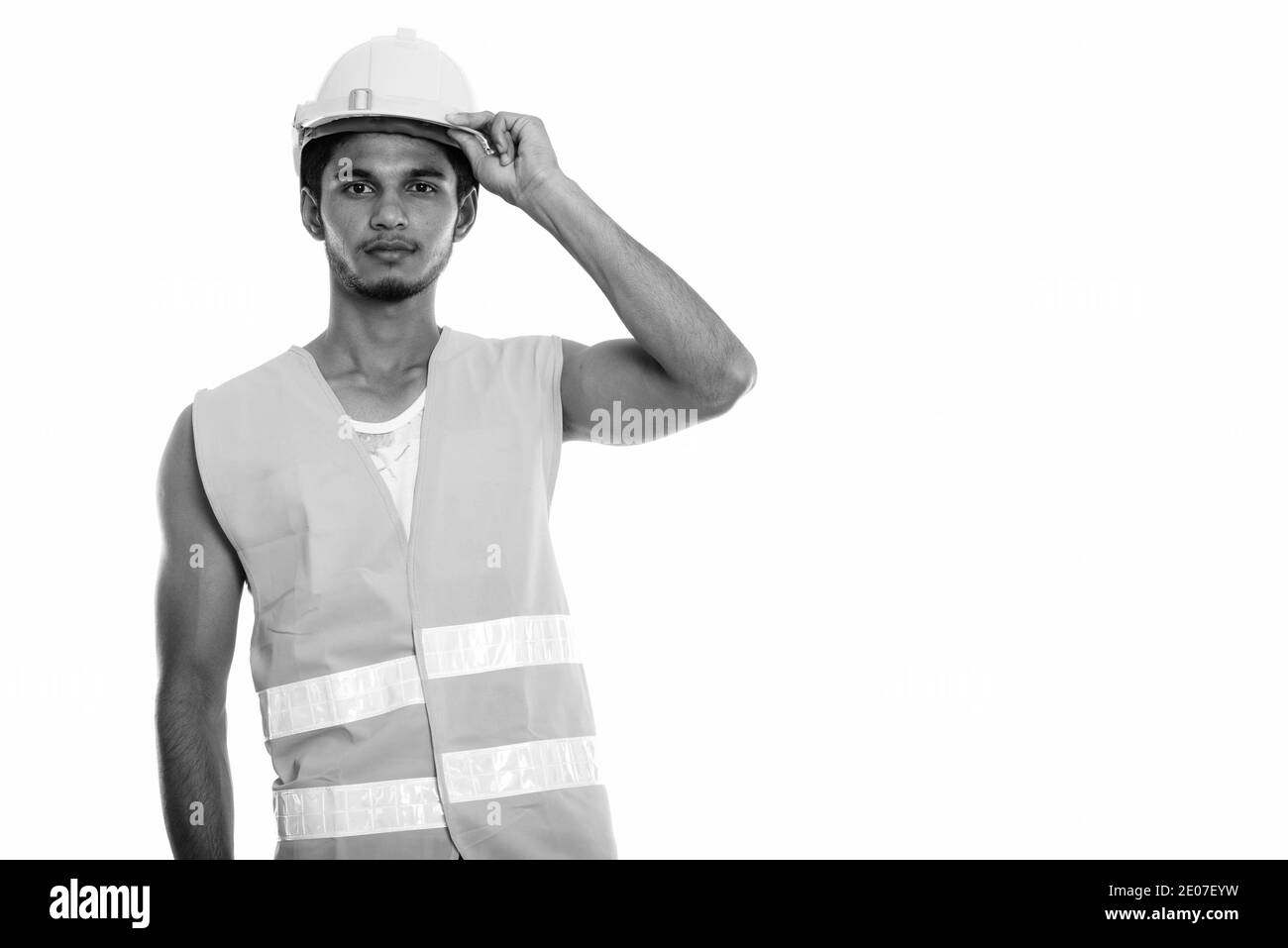 Studio shot der jungen schönen Indischen mann Bauarbeiter holding Schutzhelm auf dem Kopf Stockfoto