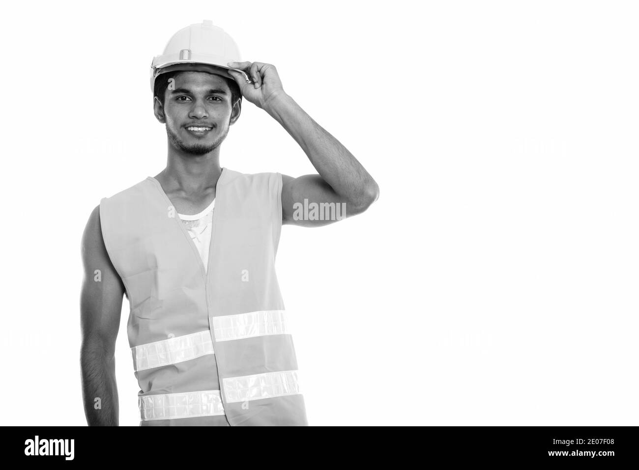 Junge glücklich Inder Bauarbeiter lächelnd, während sie Schutzhelm auf dem Kopf Stockfoto