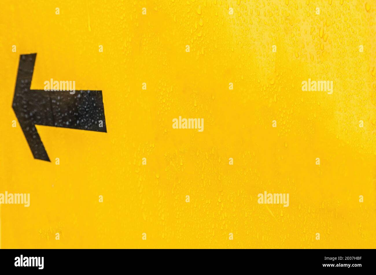 Schwarzer Pfeil auf einem gelben Straßenschild in England Stockfoto