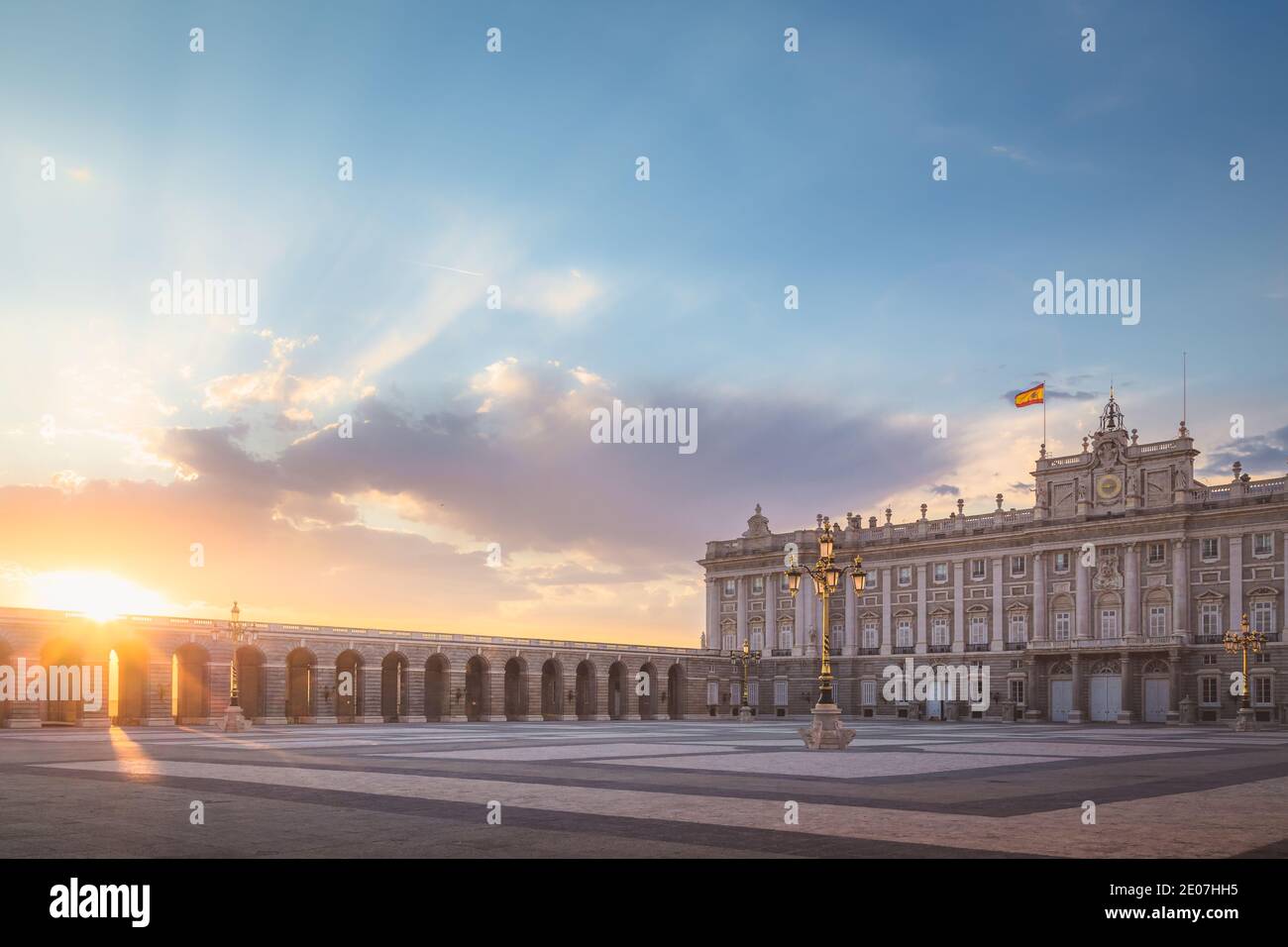 Sonnenstrahlen leuchten durch Bögen, wenn die Sonne am Königlichen Platz von Madrid untergeht, wo sich die spanische Königsfamilie in Spaniens Hauptstadt befindet. Stockfoto