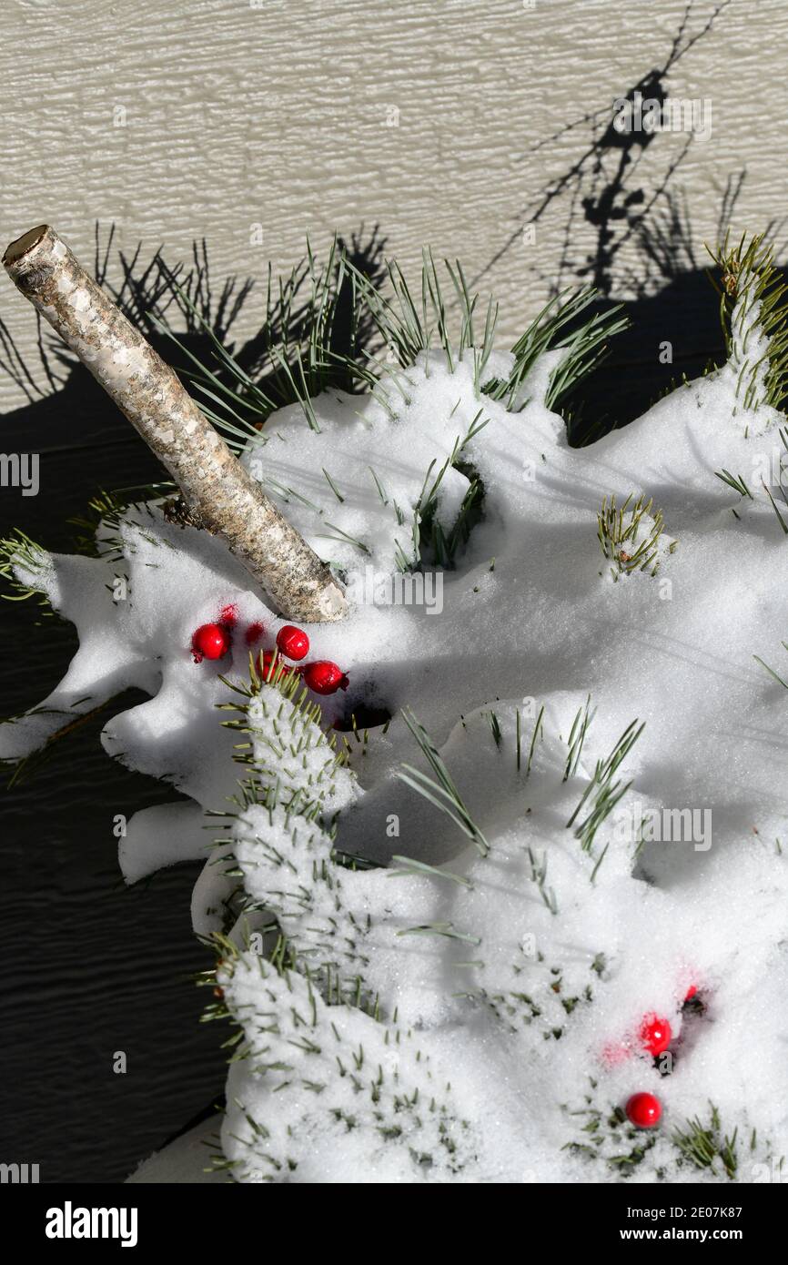 Weihnachtsdekorationen und Piniennadeln und rote Beeren bedeckt Schnee im Dezember Stockfoto