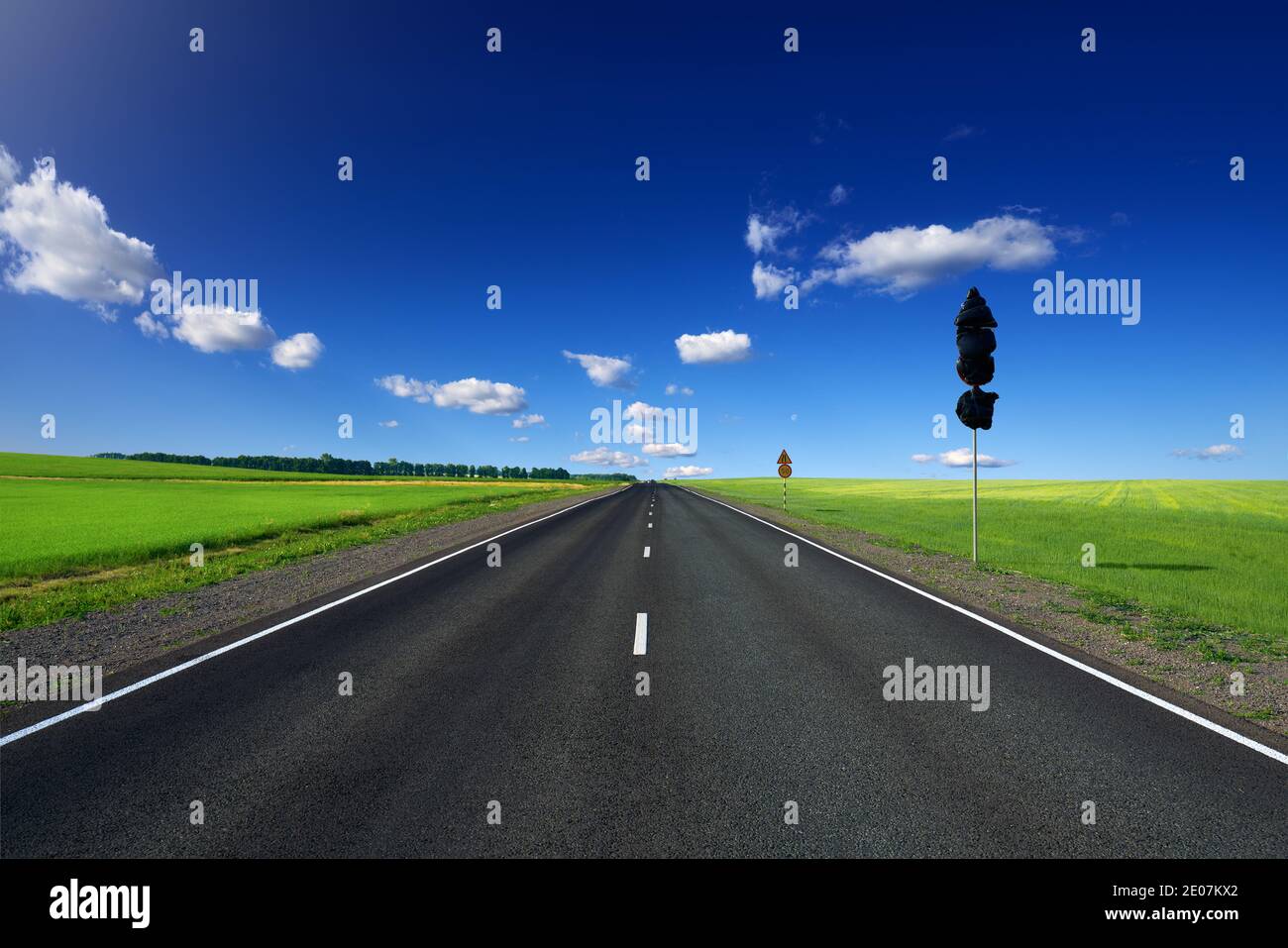 Neue Asphaltstraße mit weißen Fahrbahnmarkierungen. Das Straßenschild ist mit schwarzer Folie bedeckt, und das zweite ist gelb mit Geschwindigkeitsbegrenzung und Warnung. Auf den s Stockfoto