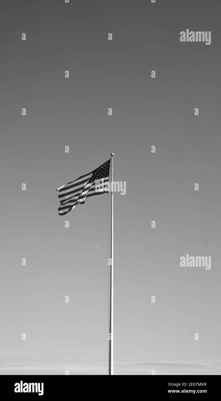 Flagge der Vereinigten Staaten, auch bekannt als amerikanische Flagge oder die US-Flagge - die Nationalflagge Amerikas, die im Wind weht. Schwarzweiß-Foto. Stockfoto