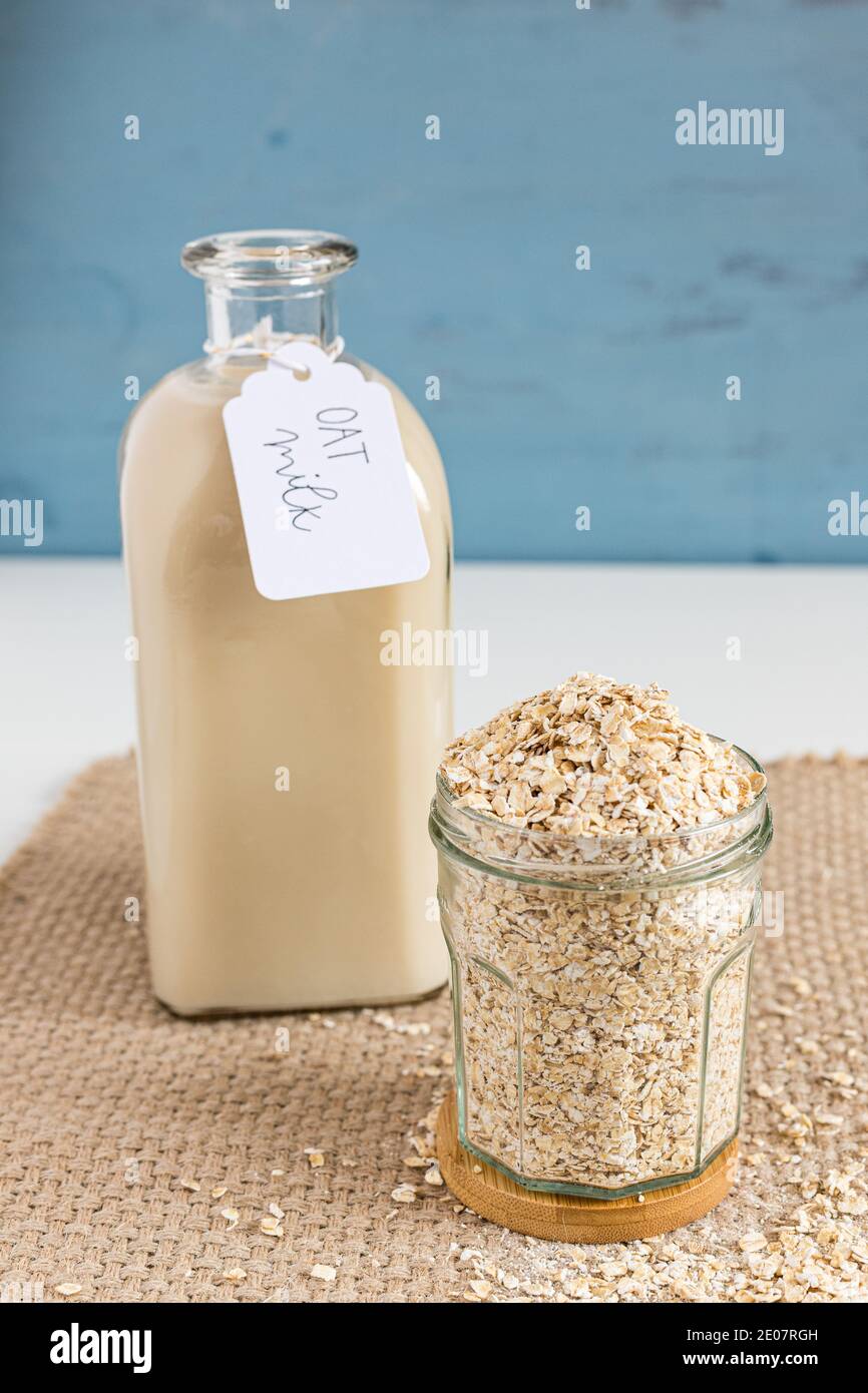 Nahaufnahme einer gekennzeichneten Hafermilchflasche neben einem Glas voller Müsli. Stockfoto