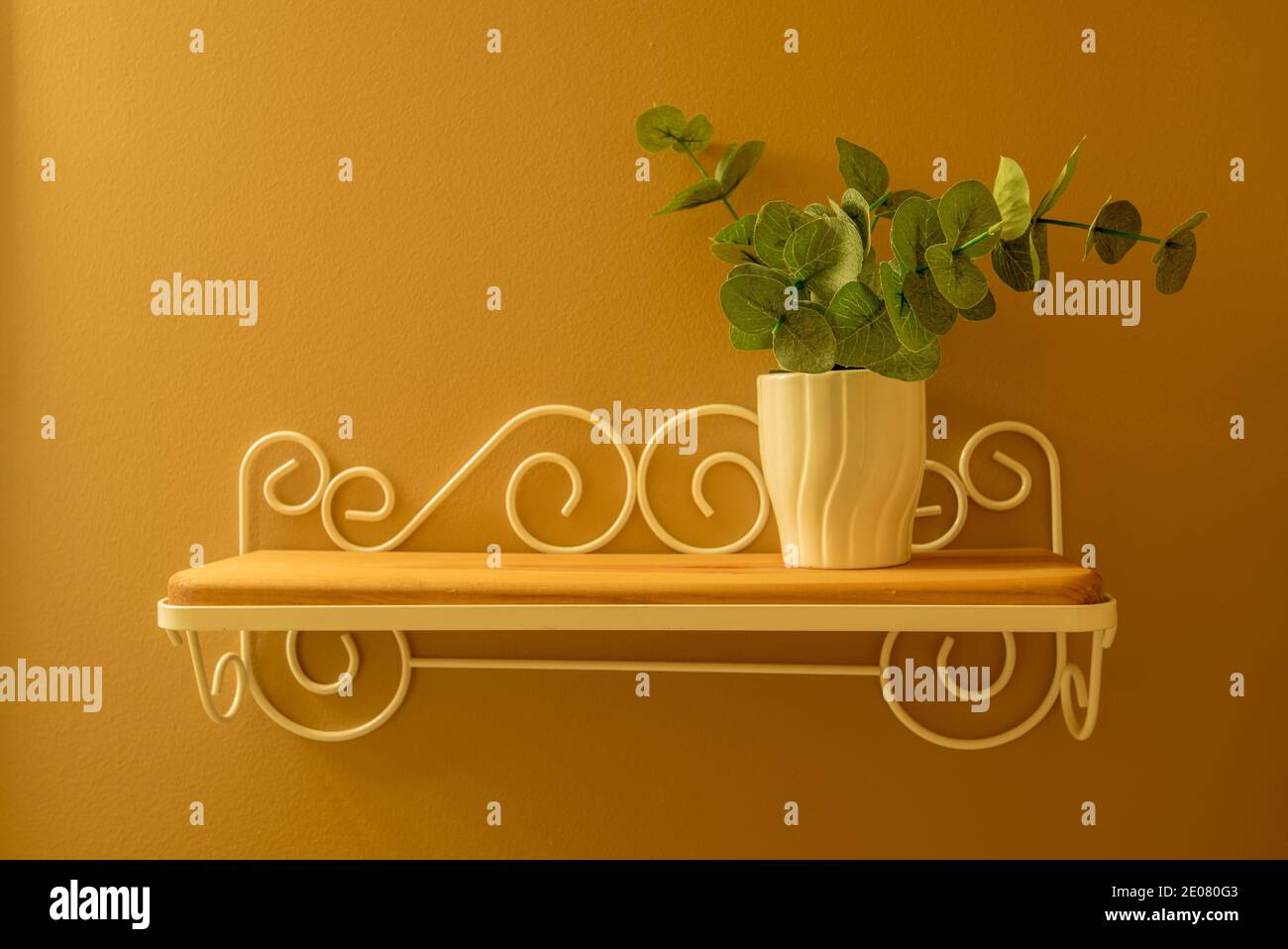 Einfache Wanddekoration mit weißer Vase und grüner Pflanze. Die einfachen Linien und Farbpalette sind auffällig, wenn sie an einer Wand mit komplementanten Farben aufgehängt werden. Stockfoto