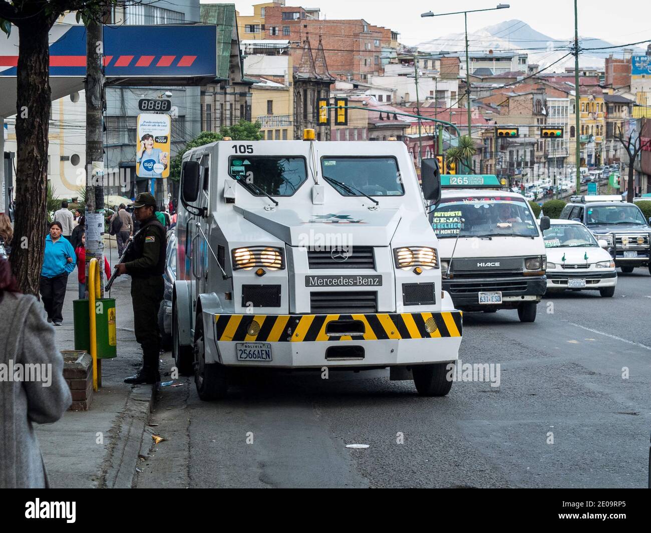 Ein Mercedes-Benz gepanzerter Sicherheitswagen überweist Bargeld vor eine Bank in La Paz, Bolivien, während ein Wachmann mit einer Schrotflinte dazusteht Stockfoto