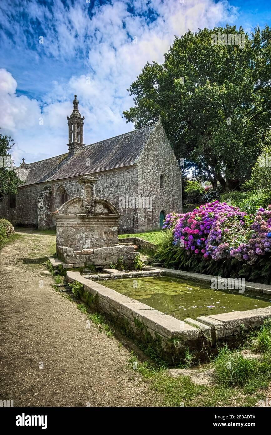 Locronan, Bretagne, Frankreich. Die alte Kapelle Notre-Dame-de-Bonne-Nouvelle befindet sich neben einem alten Brunnen. Stockfoto