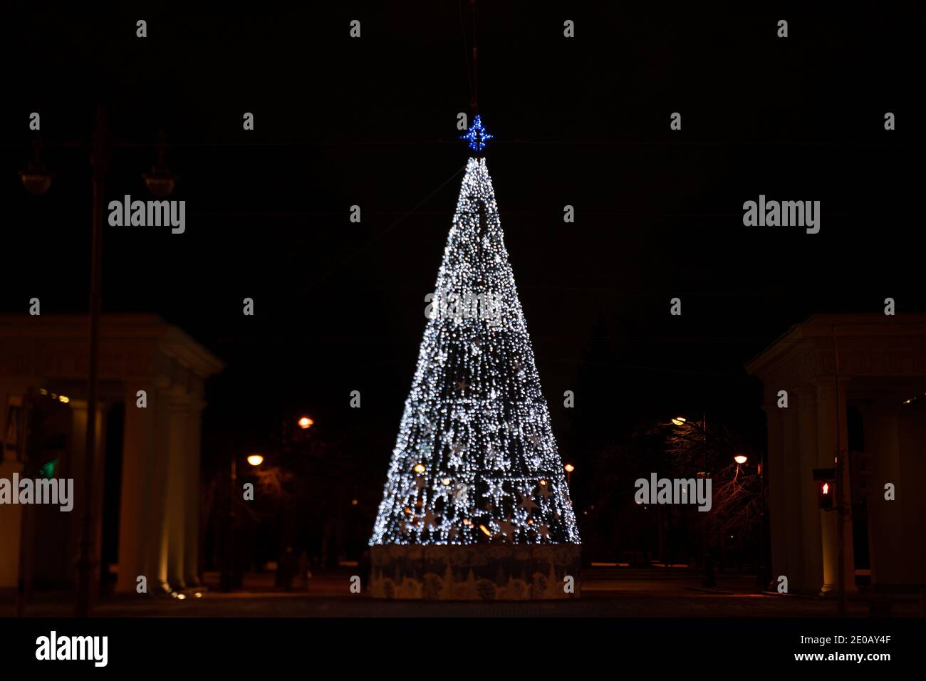 Weihnachts-/Neujahrsbaum mit weißen LED-Leuchten und blauem Topper vor dunklem Nachthintergrund in St. Petersburg, Russland Stockfoto