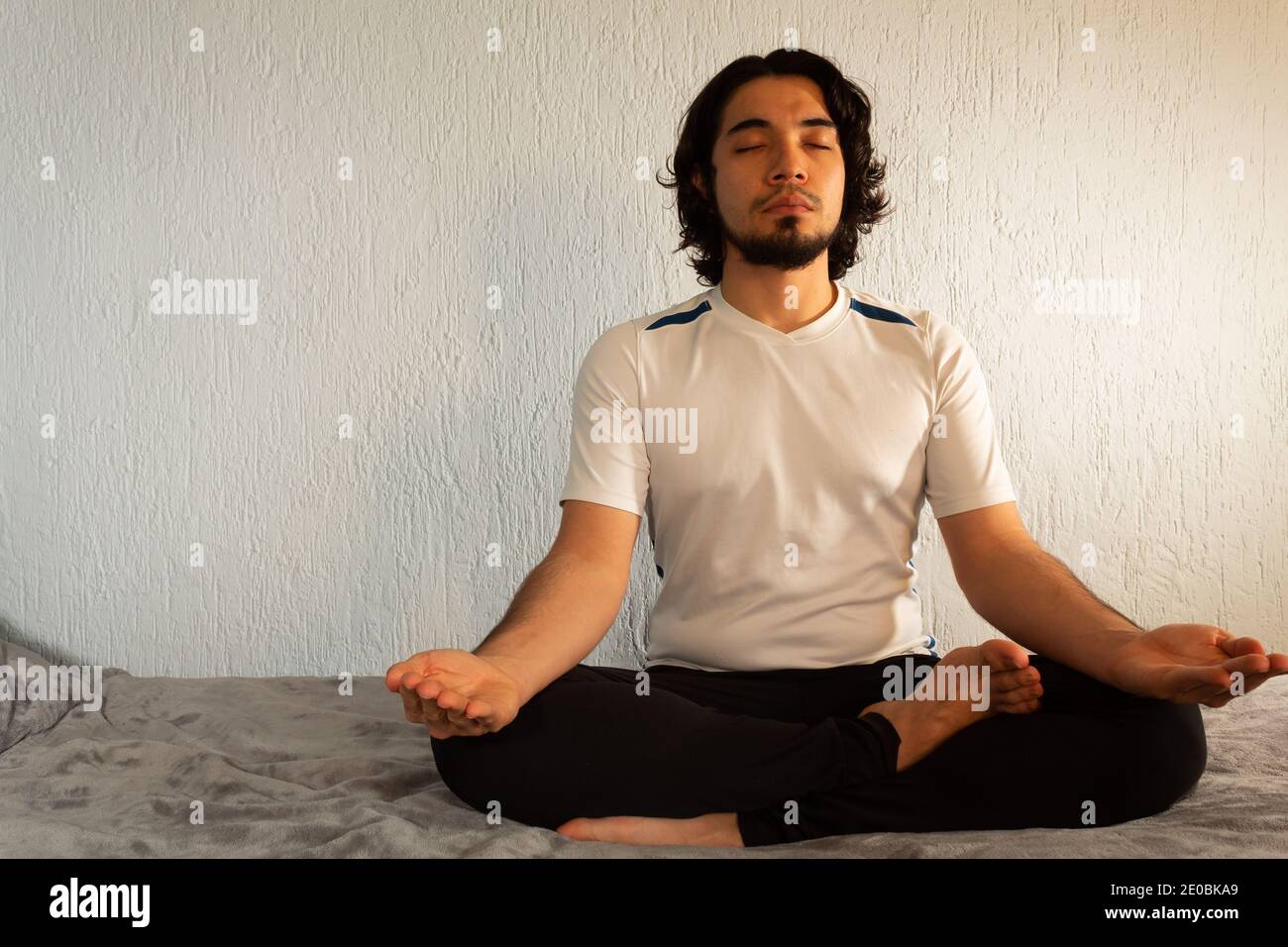 Junger hispanischer Mann mit Sportkleidung, der Yoga und Meditation praktiziert Sein Bett war sehr ruhig und friedlich Stockfoto