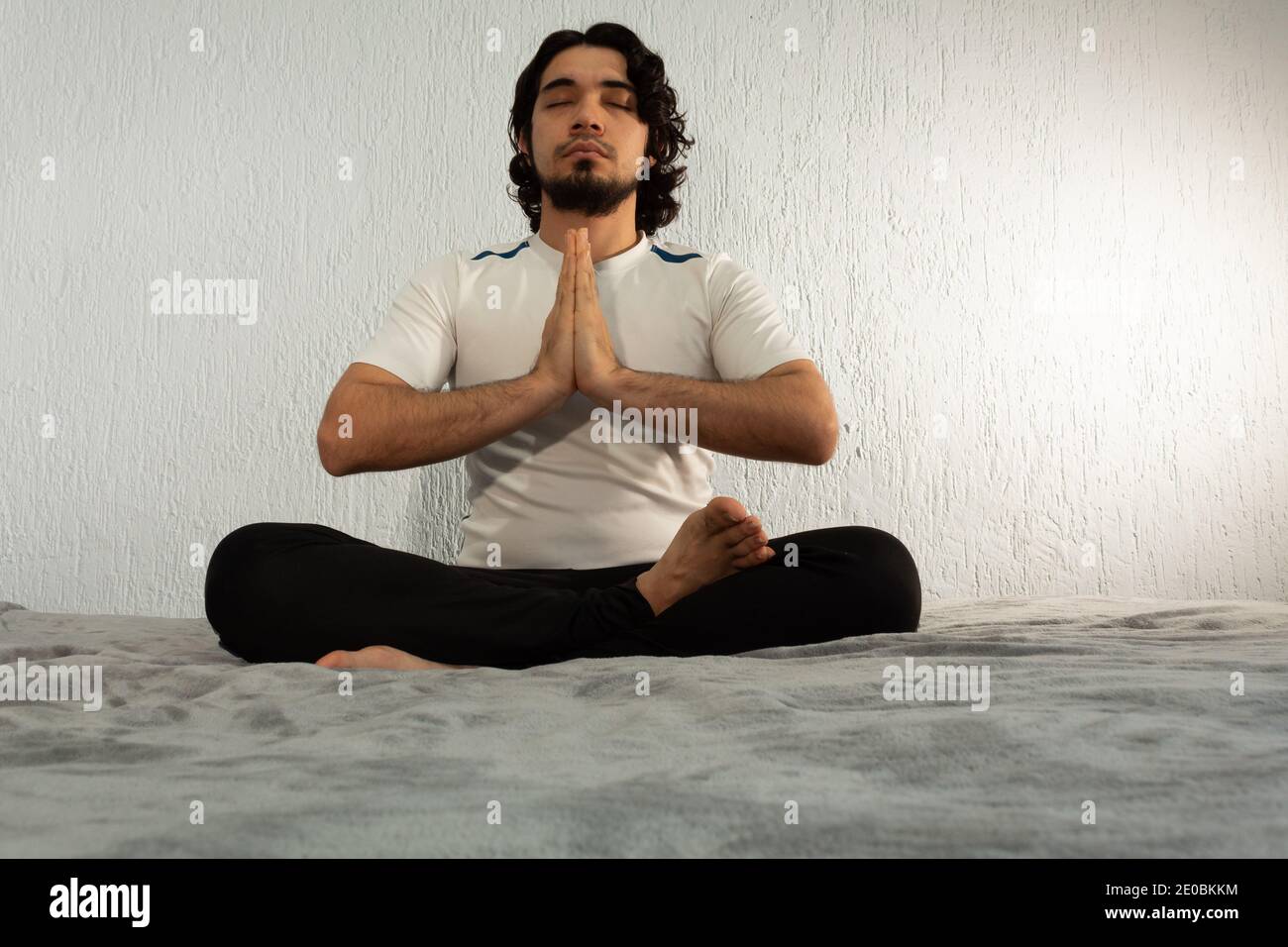 Junger hispanischer Mann mit Sportkleidung, der Yoga und Meditation praktiziert Sein Bett war sehr ruhig und friedlich Stockfoto