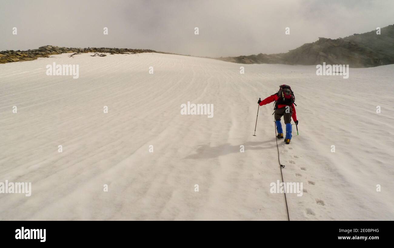 Bergsteiger klettert hinauf einen steilen Gletscher oder Schnee Steigung Stockfoto