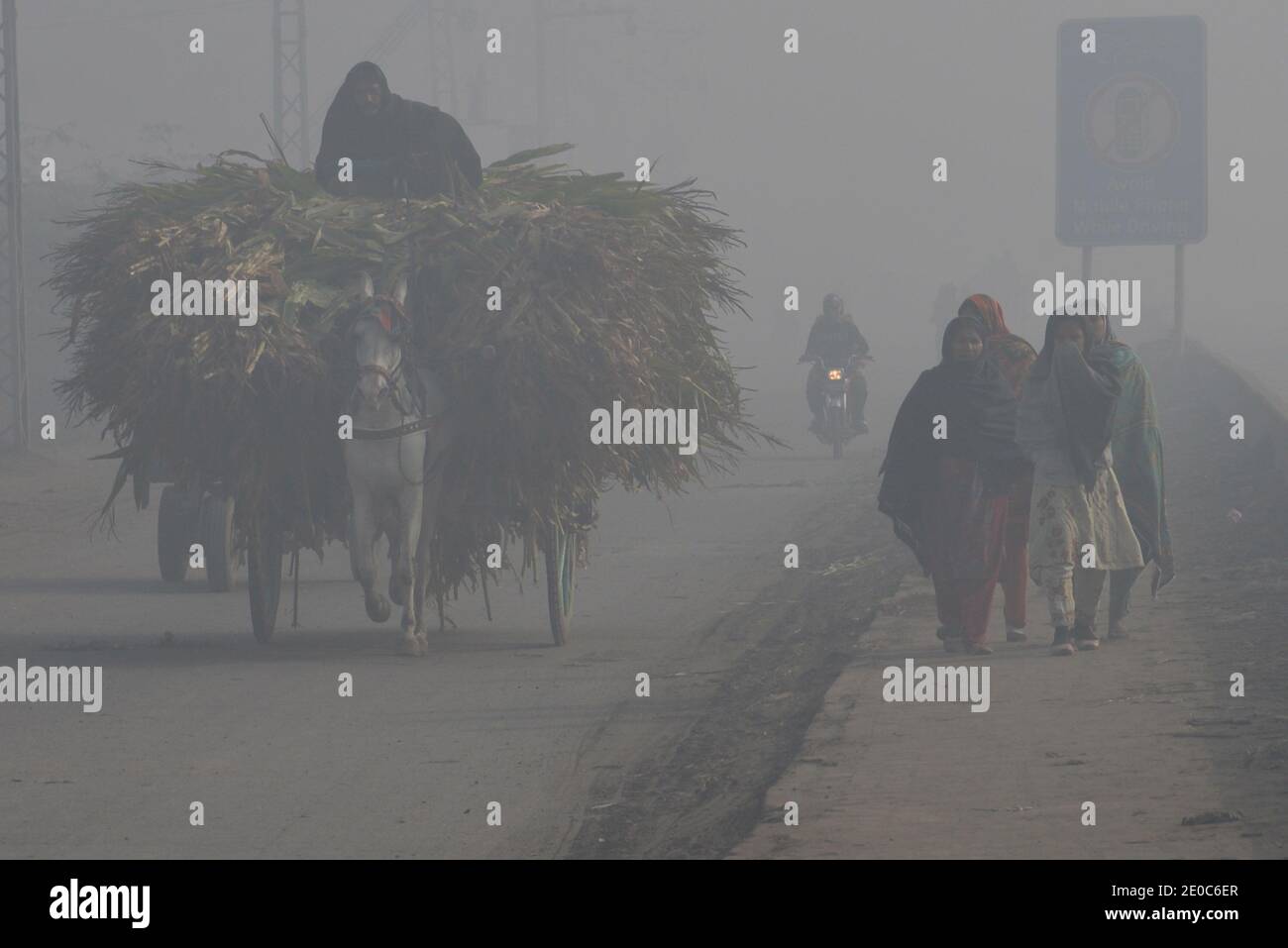 Pakistanische Pendler machen ihren Weg inmitten von schweren nebligen Bedingungen An einem kalten Winter letzten Tag des Jahres in Lahore Stockfoto