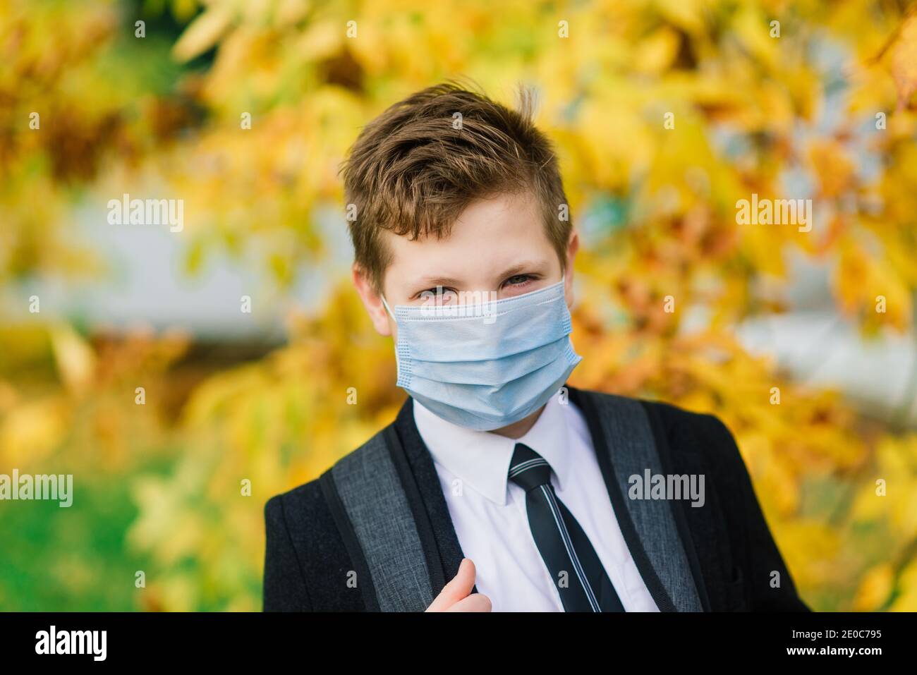 Schuljunge geht aus der Schule tragen Schutzmaske in der Stadt Stockfoto