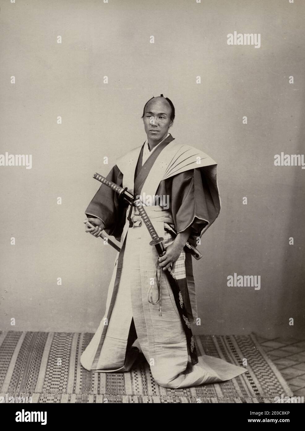 Vintage-Fotografie aus dem 19. Jahrhundert - Samurai mit zwei Schwertern in langen Hosen, Studio-Setting. Japan, um 1880. Wahrscheinlich von einem Schauspieler gestellt. Stockfoto