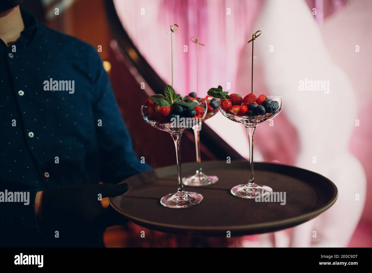 Kellner serviert ein Gericht in einem Restaurant mit Glas Beeren. Stockfoto