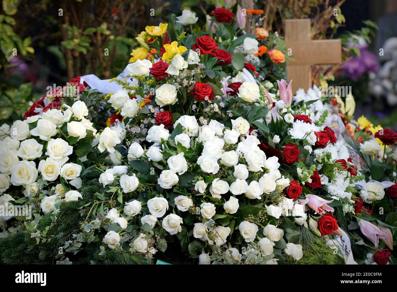 Viele Blumen nach einer Beerdigung auf einem Grab mit einem Holzkreuz Stockfoto