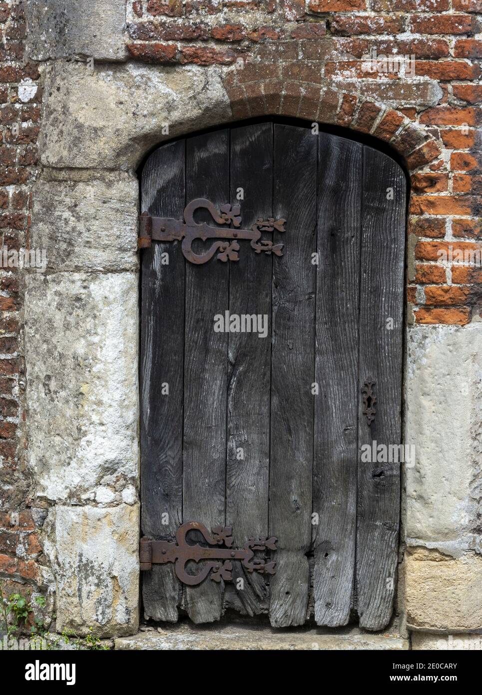 Große verwitterte Holztür mit großen rostigen Scharnieren Stockfoto