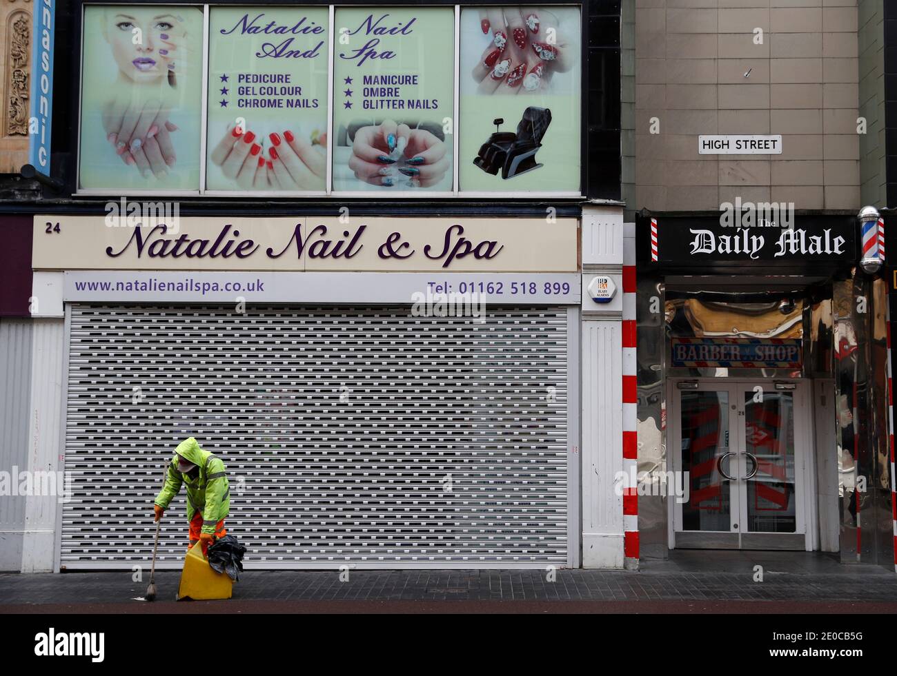 Leicester, Leicestershire, Großbritannien. Dezember 2020. Ein Straßenputzer arbeitet vor einem Nagel-Spa und Barbiere, nachdem sie gezwungen wurden, zu schließen, nachdem die Stadt Tier 4 der Coronavirus-Beschränkungen betrat. Credit Darren Staples/Alamy Live News. Stockfoto