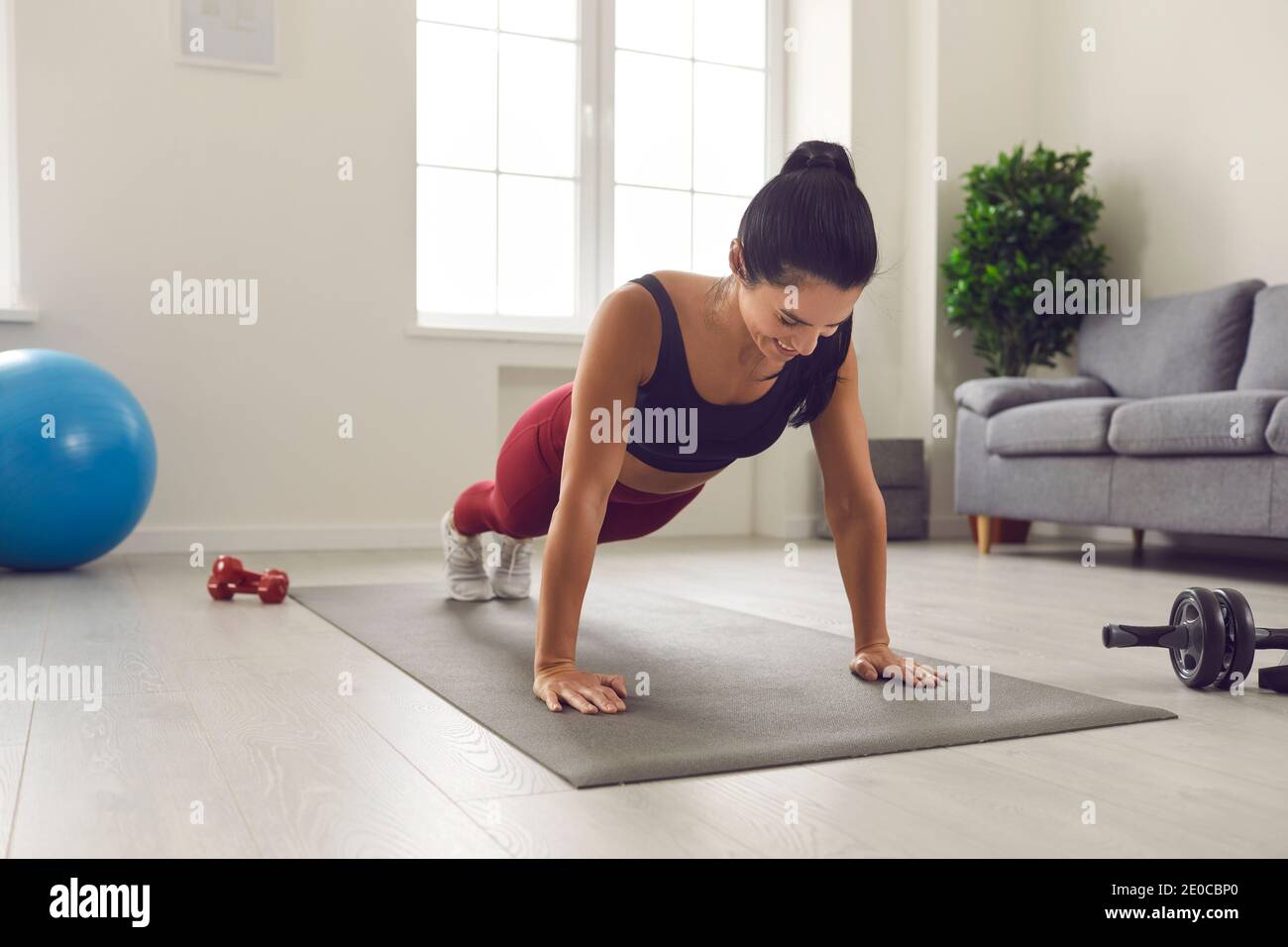 Fröhliche junge Frau tun volle Planke auf Sportmatte während Fitnesstraining zu Hause Stockfoto