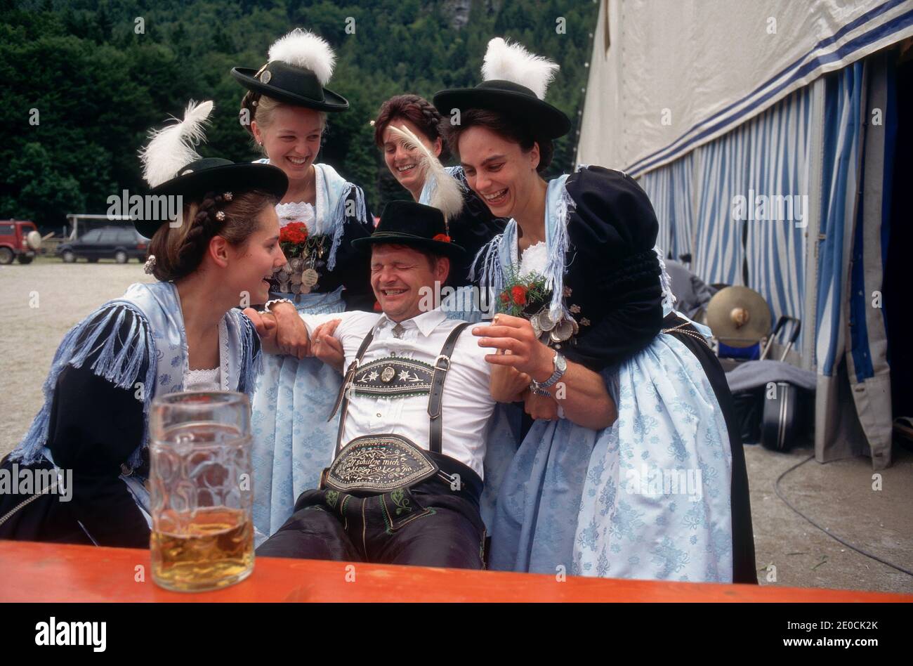 Deutschland /Bayern /Frau hilft einem betrunkenen Mann in traditioneller bayerischer Kleidung beim örtlichen Bierfest. Stockfoto