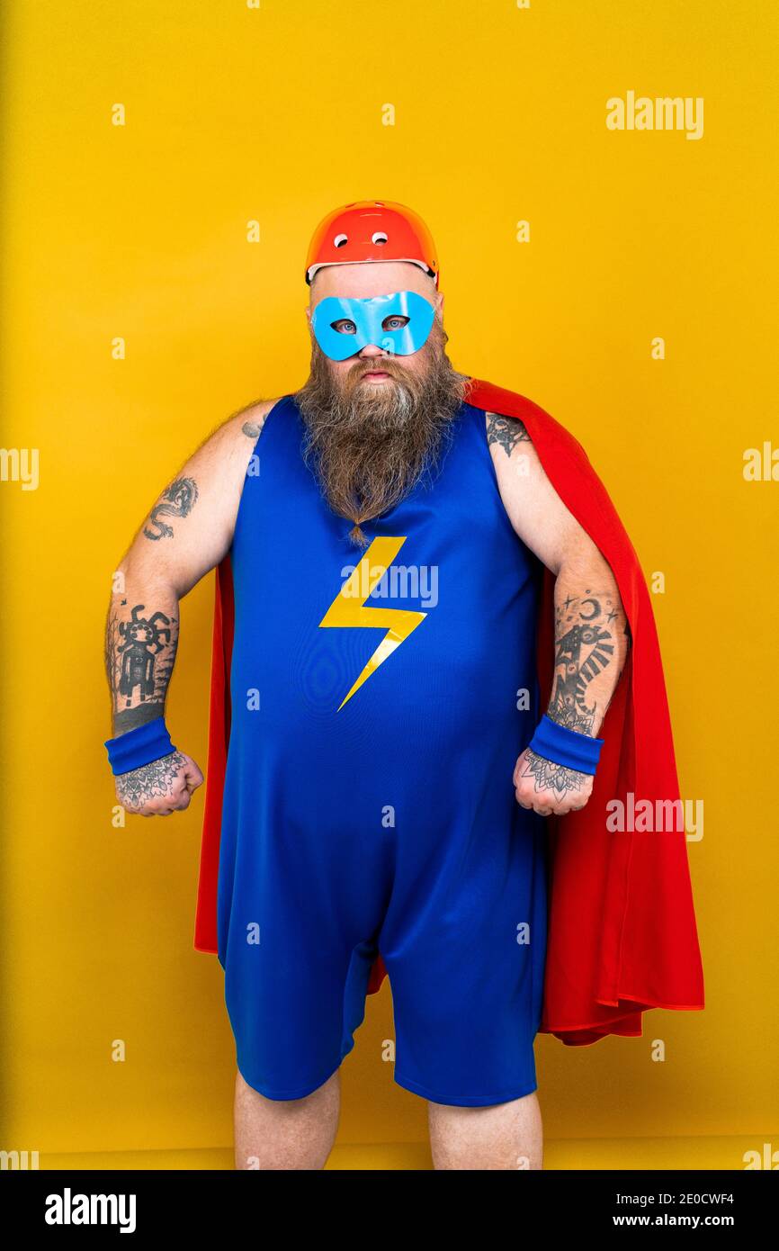 Lustige fetten Mann mit Superhelden Kostüm als Supermensch mit besonderen Kräften, Porträt auf farbigem Hintergrund Stockfoto