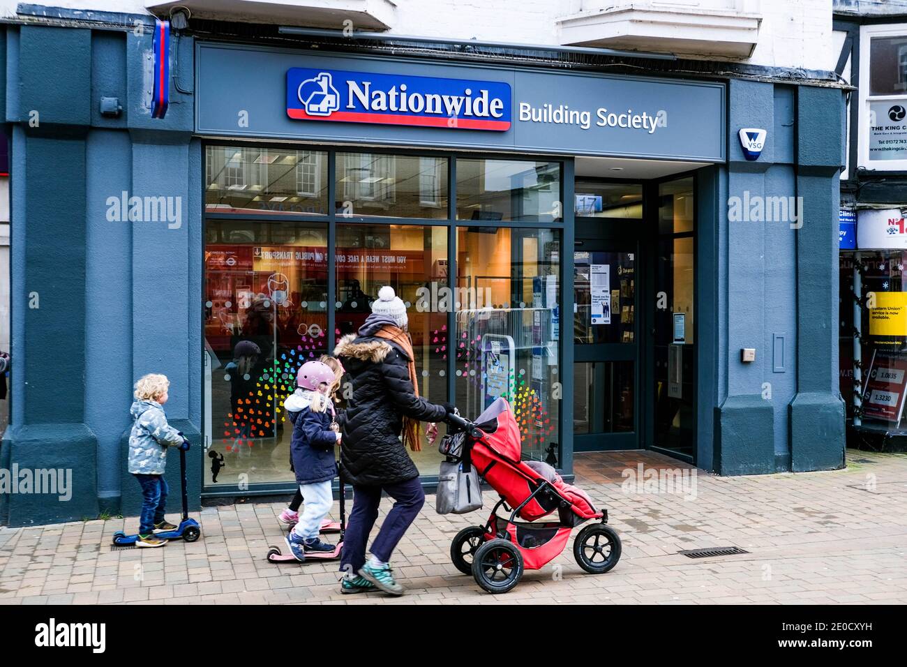 London, Großbritannien, Dezember 31 2020, Mutter und Kinder, die während der COVID-19 Tier 4 Absperrung an EINER High Street Filiale der Nationwide Building Society vorbeigehen Stockfoto