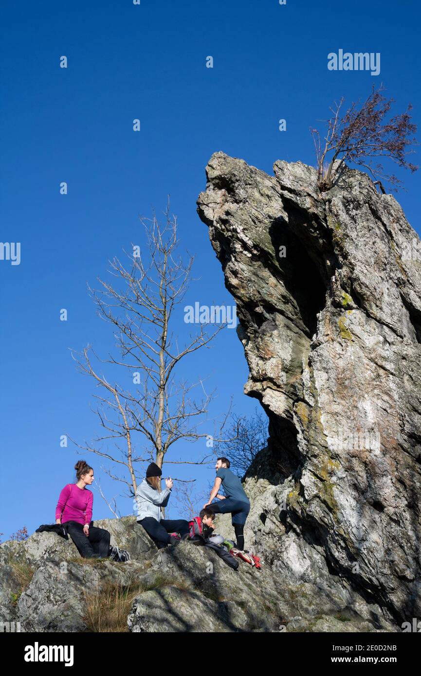 Velky Rabstejn, Tschechische Republik / Tschechien - 7. November 2020: Touristen stehen unter Felsen und Steinen. Zerklüftete Klippe in der Natur. Klarer blauer Himmel in au Stockfoto