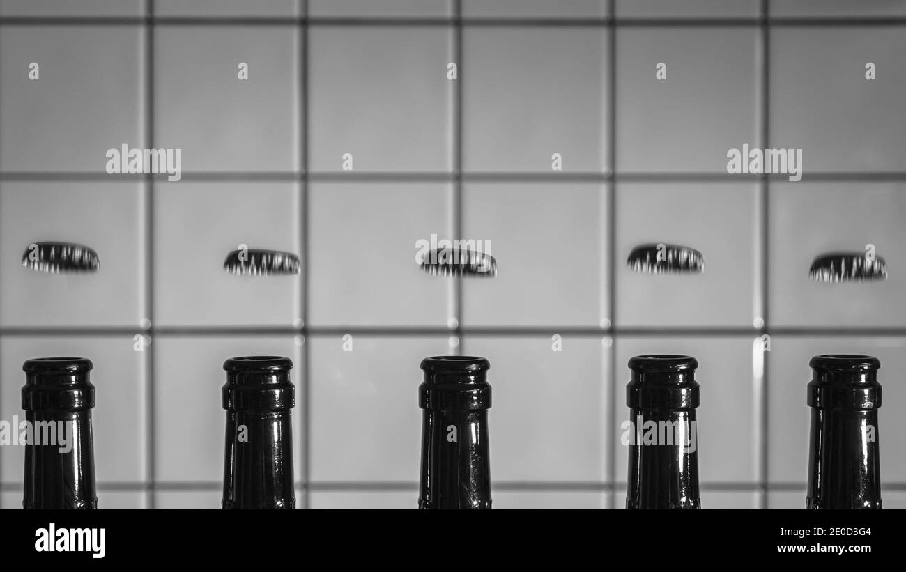 Fünf Bierflaschen, deren Oberteile ab und nach oben fliegen In einem breiten Schwarzweiß-Bild Stockfoto