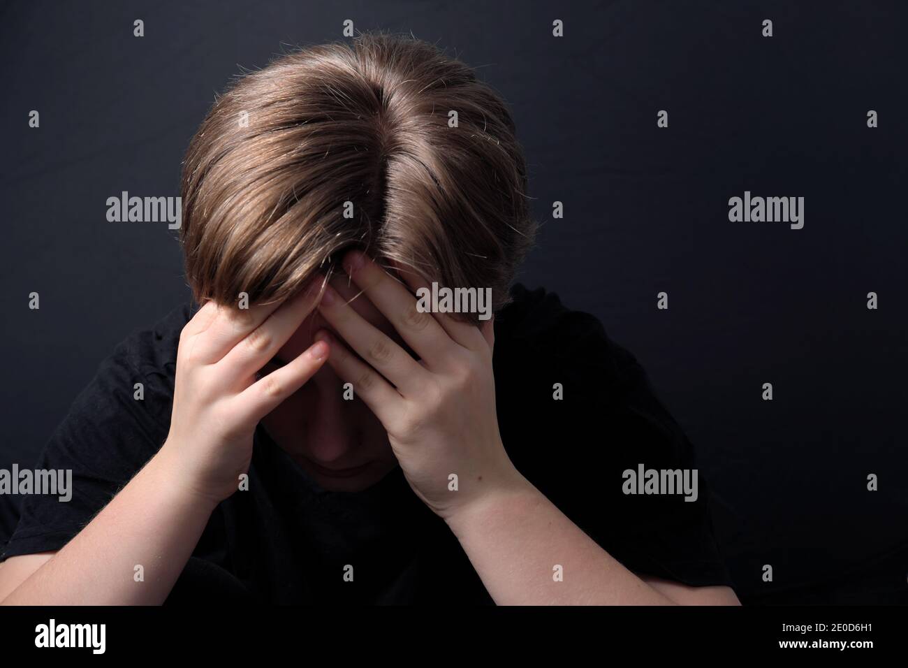 Teenager sitzt in einer geschlossenen Haltung mit psychischen Problemen Wie z. B. Depression während der COVID-19-Sperre Stockfoto