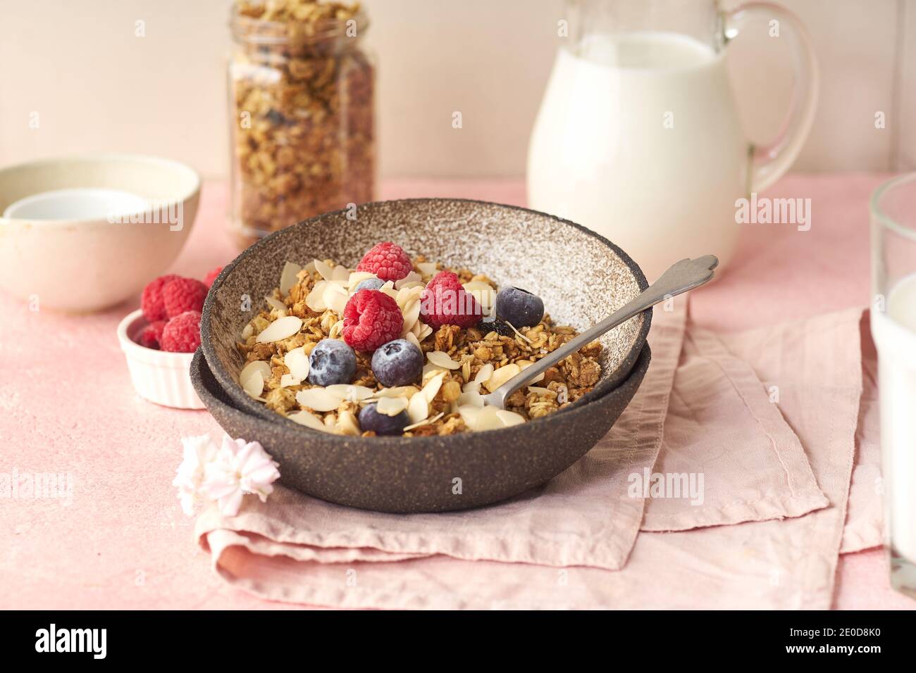 Eine Schüssel Müsli mit Nüssen und Hafer serviert mit Beeren und Milch Stockfoto