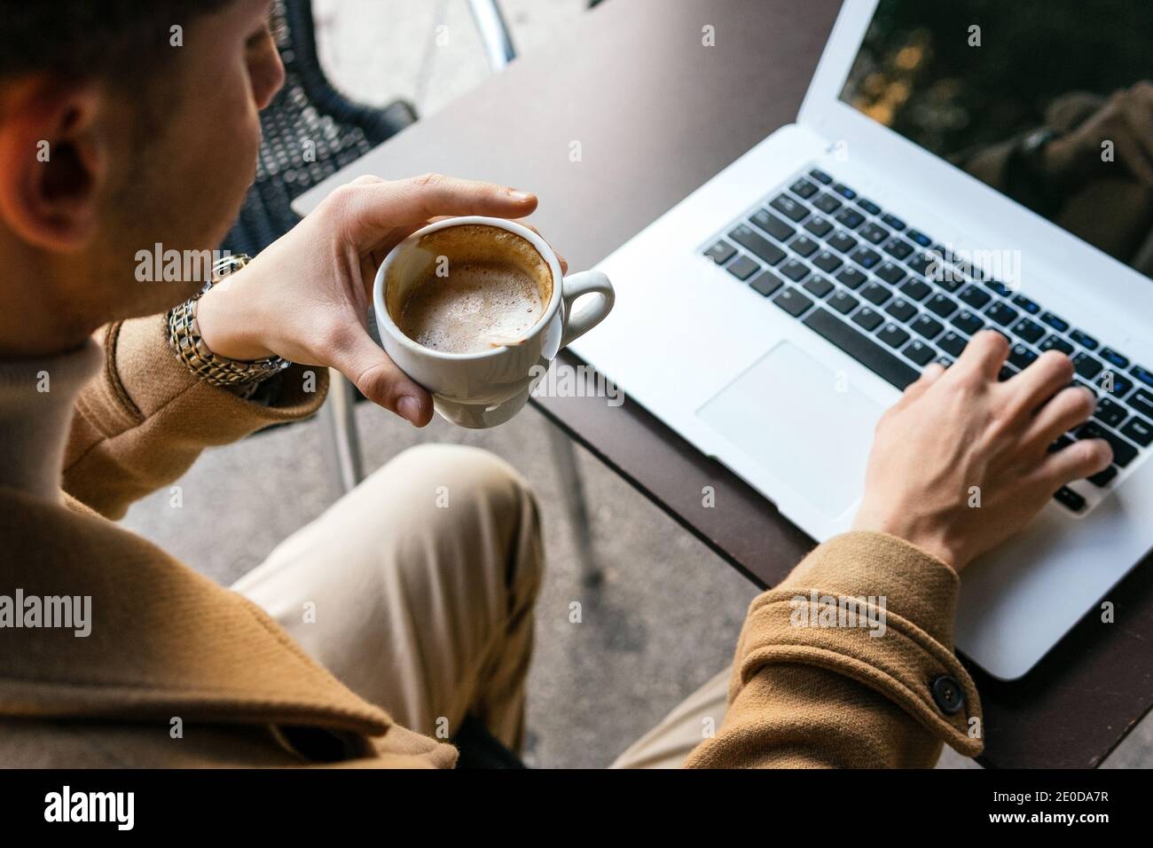 Von oben Ernte anonymen männlichen Unternehmer sitzt im Café mit tasse Kaffee und Tippen auf Netbook während der Arbeit an Projekt online Stockfoto