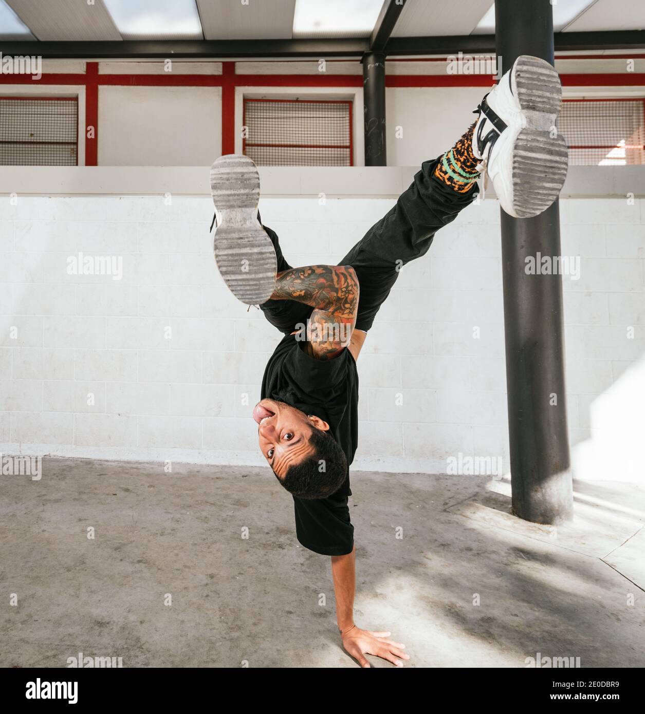 Voller Körper von energischen jungen Mann dabei akrobatische Handstand während Break Dance Stockfoto