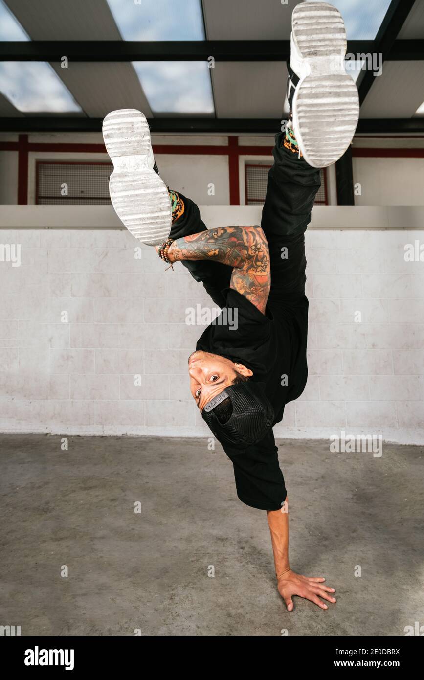 Voller Körper von energischen jungen Mann dabei akrobatische Handstand während Break Dance Stockfoto