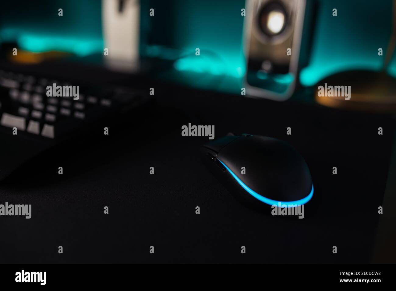 Von oben schwarze Tastatur mit blau beleuchteten Buchstaben platziert Auf dem Schreibtisch in der Nähe des Computermonitors Stockfoto