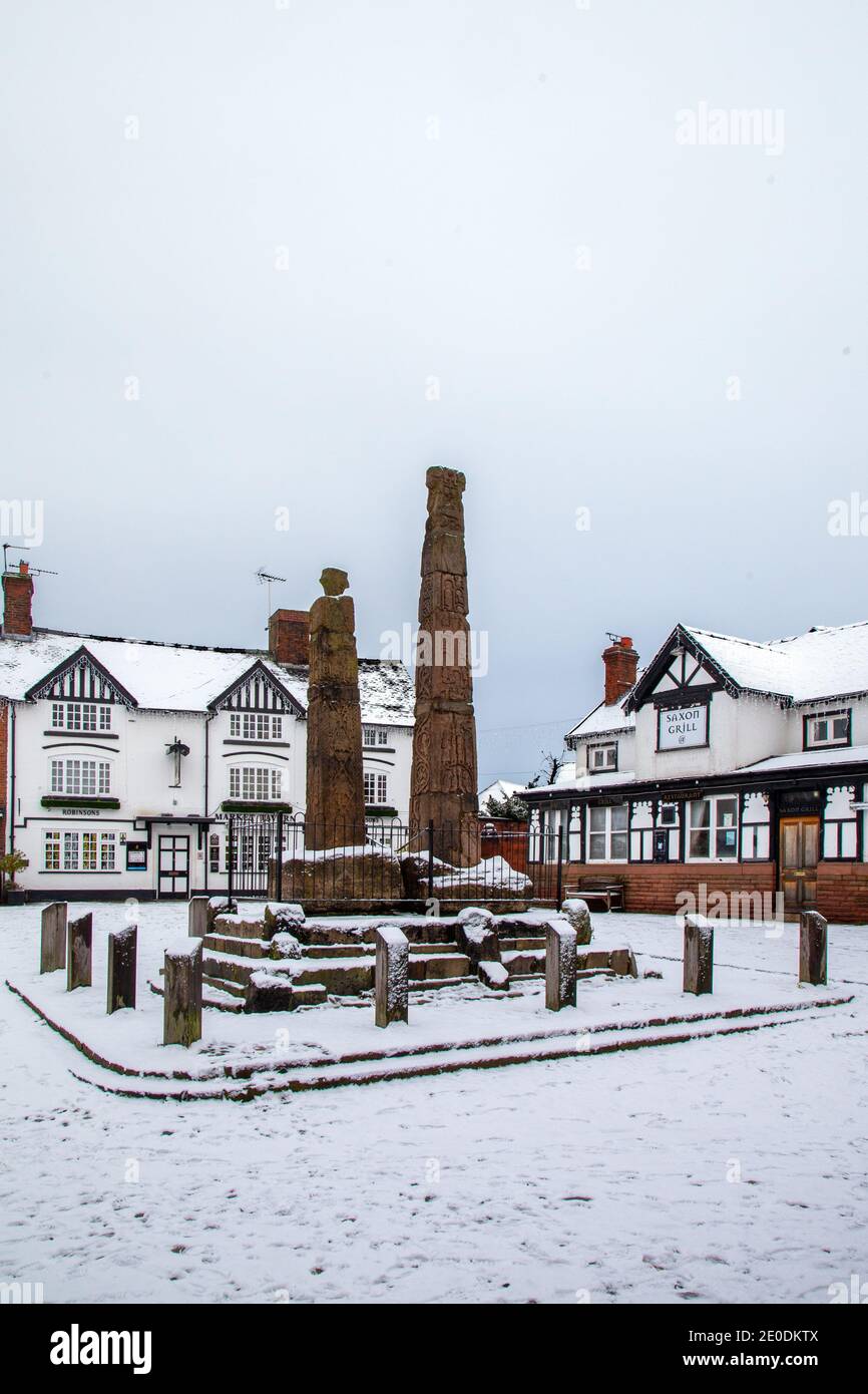 Alte sächsische Steinkreuze auf dem gepflasterten schneebedeckten Marktplatz im Winter in Sandbach-Tscheshire vor dem Gasthaus Market Tavern Stockfoto