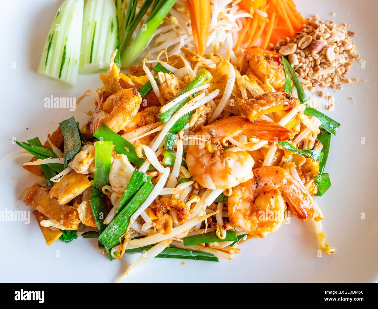 Das klassische Thai Dish Pad Thai, bestehend aus gebratenen Nudeln mit Garnelen, Bohnensprossen, gebratenem Tofu, zerkleinerten Erdnüssen und Frühlingszwiebeln, mit Gurke und Stockfoto