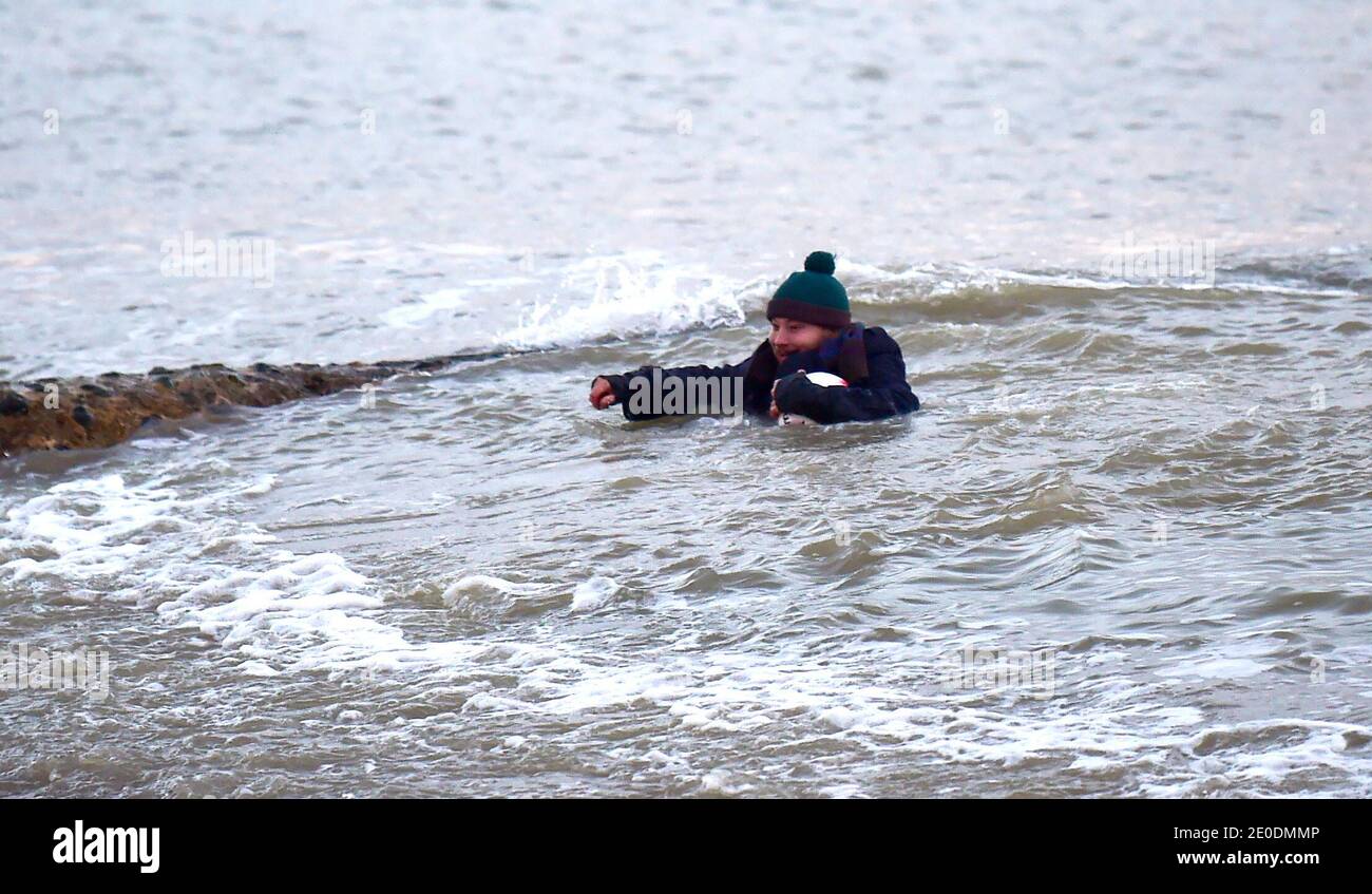 Brighton UK 31. Dezember 2020 - dieser Kerl wird durchnässt, als er seinen Fußball aus dem Meer am Brighton Strand rettet, während die Sonne am 2020 entlang der Südküste von Großbritannien untergeht. Kredit Simon Dack / Alamy Live Nachrichten Stockfoto