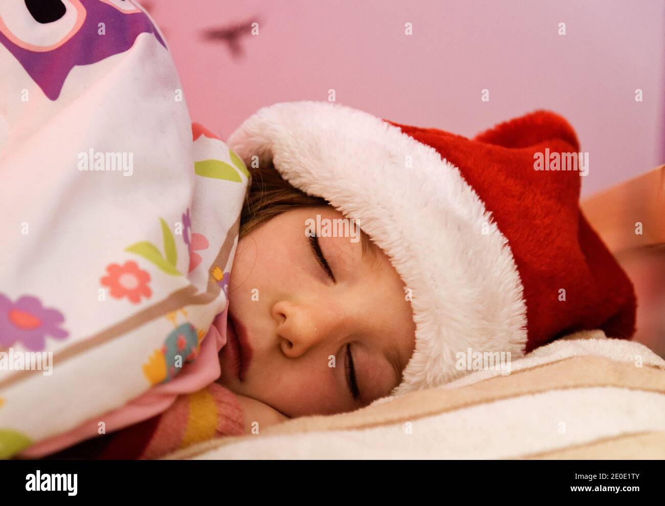 Ein kleines Mädchen (6 Jahre alt) Schlafend im Bett mit ihrem weihnachtshut an Stockfoto