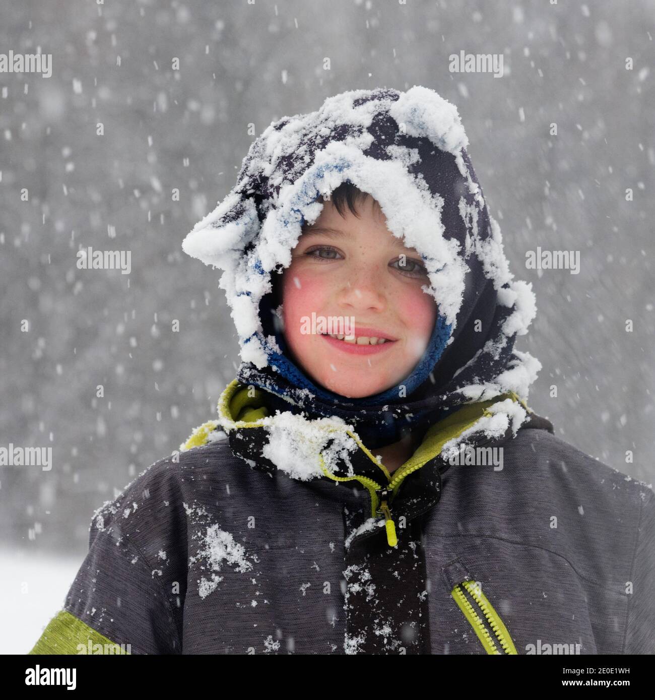 Porträt eines Jungen (8 Jahre alt) draußen im fallenden Schnee in Quebec, Kanada Stockfoto