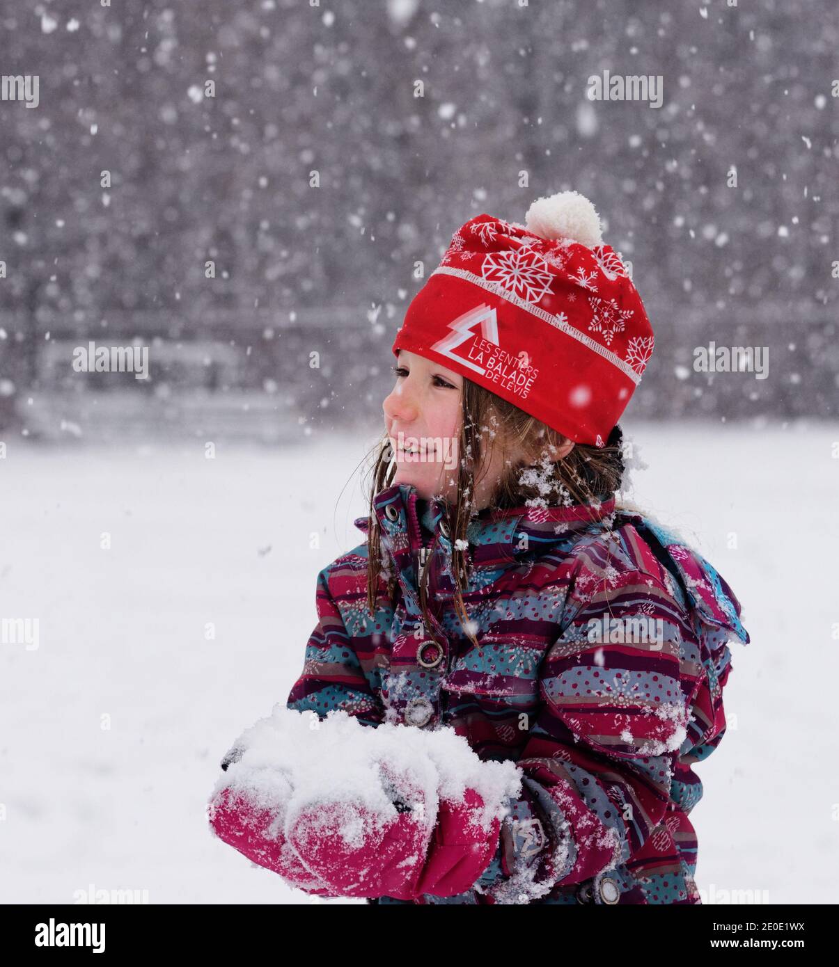 Porträt eines kleinen Mädchens (6 Jahre alt) draußen im fallenden Schnee in Quebec, Kanada Stockfoto