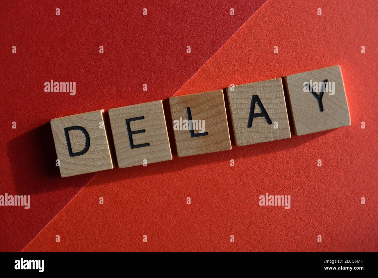 Verzögerung, Wort in Holzbuchstaben isoliert auf rotem Hintergrund Stockfoto