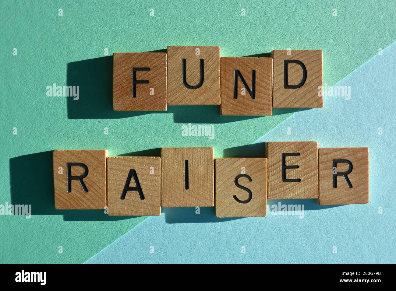 Fund Raiser, Wörter in hölzernen Buchstaben auf blauem Hintergrund isoliert Stockfoto