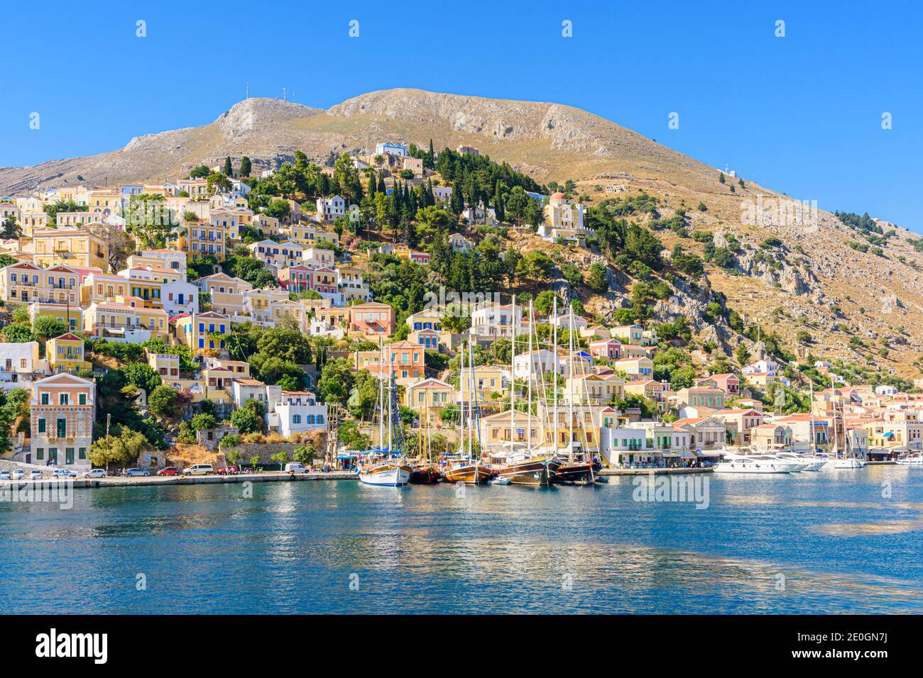 Symi Blick auf die Stadt von Booten, die entlang der Küste auf der Insel Symi, Dodekanes, Griechenland, festgemacht sind Stockfoto