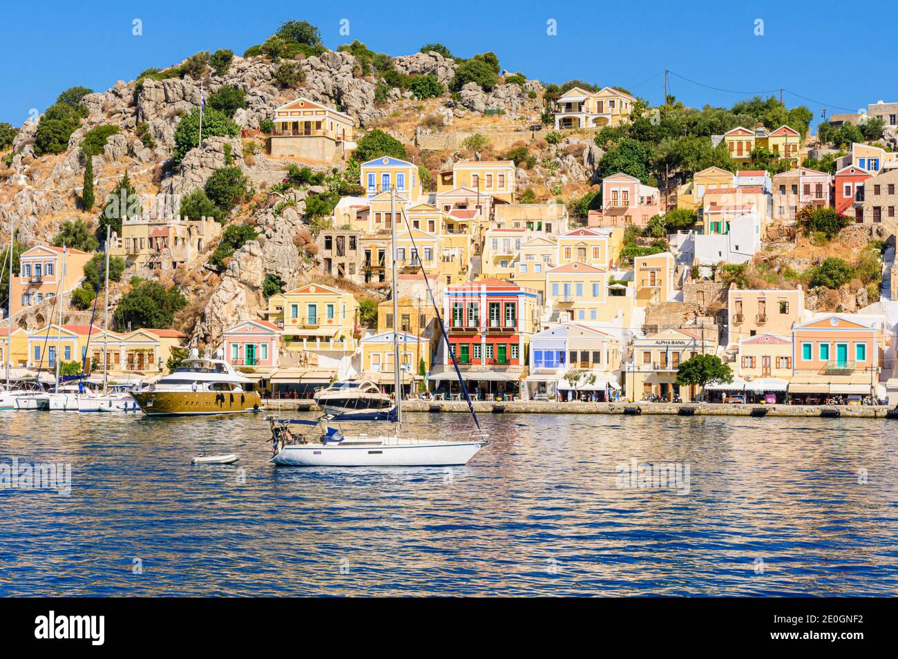 Eine Yacht fährt vom malerischen Hafen von Yialos Town, auf der Insel Symi, Dodekanes, Griechenland ab Stockfoto