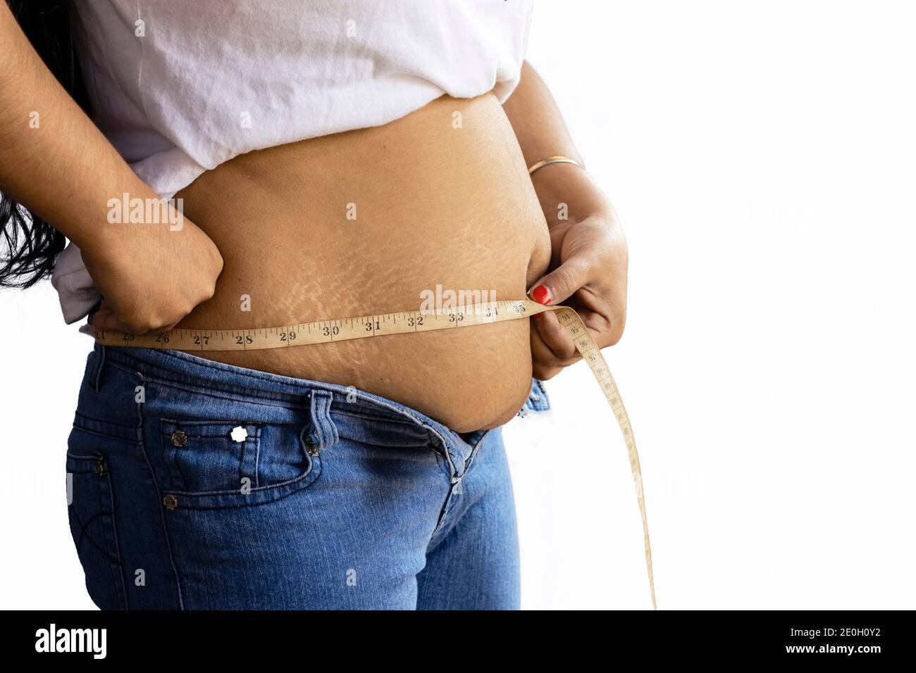 Mittlere Seitenansicht einer indischen Frau, die Fett misst Bauch mit Klebeband auf weißem Hintergrund Stockfoto