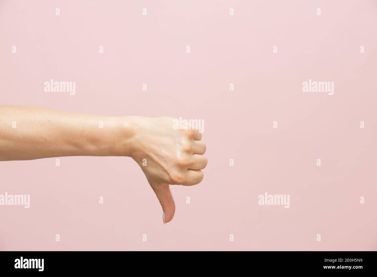 Weibliche kaukasische Hand zeigt Daumen nach unten Geste, auf rosa Hintergrund. Minimalkonzept. Speicherplatz kopieren Stockfoto