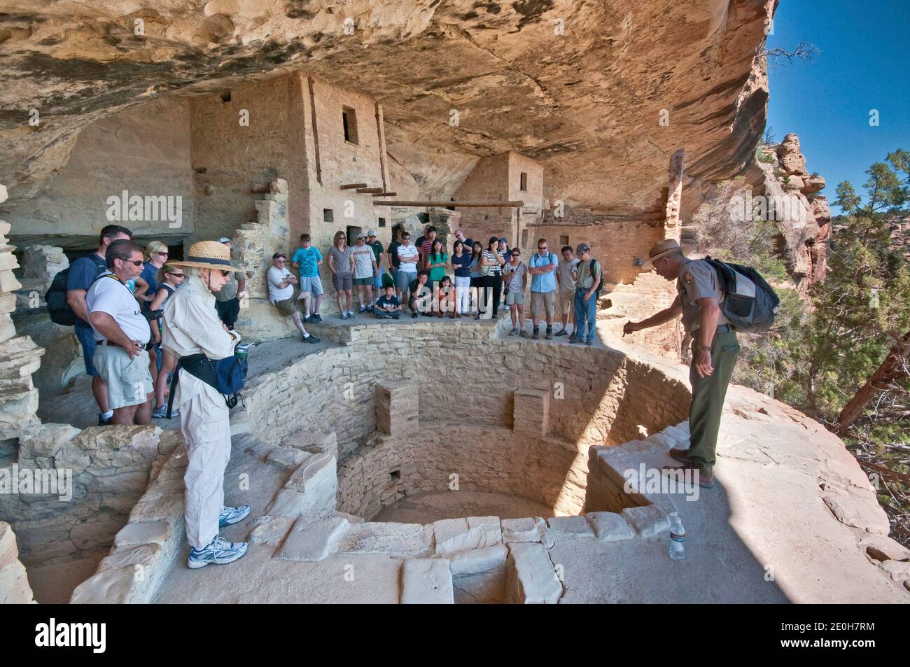 Parkführer und Besucher über Kiva (zeremonielle Kammer) im Balcony House Cliff Dwelling, Cliff Palace Loop, Mesa Verde National Park, Colorado, USA Stockfoto